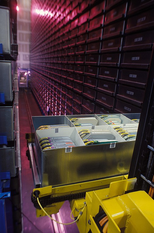Picture showing a Automated Storage and Retrieval System (ASRS) located at the Defense Visual Information Center. Source: https://commons.wikimedia.org/wiki/File:Automated_Storage_and_Retrieval_System_-_Defense_Visual_Information_Center_%C2%B7_DD-ST-96-00253.JPEG